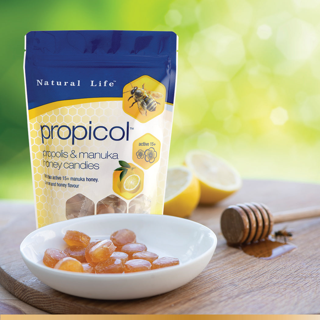 Natural Life Propicol - Propolis & Manuka Honey Candies stock photo with plate of candies, lemons and stick of honey
